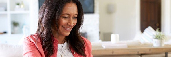 Smiling woman sits in her home after applying for a Furnished Holiday Let mortgage product with Marsden Intermediaries.