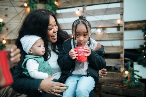 Young girl sitting on her mother's knee enjoying a hot chocolate