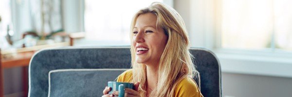 Young woman sat in an armchair smiling to represent Expat Residential case study