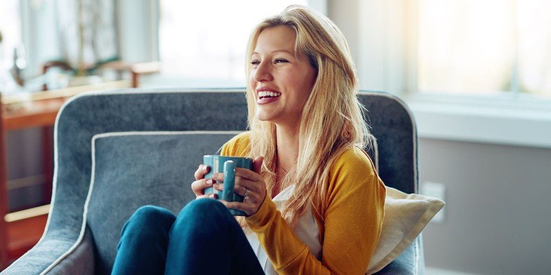 Young woman sat in an armchair smiling to represent Expat Residential case study